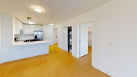 Located on the 9th floor of One123 in Union City, NJ, this well-appointed 2-bedroom, 2-bathroom residence offers a thoughtfully designed open-concept layout with clean, modern finishes throughout. Light wood flooring flows seamlessly across the living, dining, and bedroom areas, creating a warm and cohesive aesthetic against the crisp white walls and ceilings.

The kitchen is a standout feature, showcasing high-gloss white upper cabinetry, dark lower cabinets, stainless steel appliances including a French door refrigerator, electric range, and built-in microwave. A generous white quartz peninsula with an integrated sink provides additional workspace and casual seating, opening directly to the living area for effortless entertaining.

Both bedrooms are well-proportioned, bathed in natural light from large windows with urban views, and include dedicated closet space. The two bathrooms are finished with light tile flooring, warm wood vanities topped with white countertops, mirrored medicine cabinets, and polished chrome fixtures. One bathroom features a soaking tub with a tiled shower surround, while the second includes accessibility-friendly grab bars.

A stacked in-unit washer and dryer is conveniently housed in a dedicated closet within the main living area, adding everyday practicality to this modern residence.