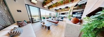 This 580 square foot rooftop space in San Diego is a masterpiece of modern design and urban luxury. The area seamlessly blends indoor and outdoor living, featuring multiple distinct zones for relaxation and entertainment. Large sliding glass doors open to create a fluid transition between the interior lounge and the expansive terrace.

The outdoor area boasts a variety of seating options, from comfortable sofas and armchairs to bar-height tables, catering to different social scenarios. A striking pergola with intricate cut-out patterns provides partial shade and visual interest. Carefully curated landscaping, including raised planters with drought-resistant vegetation, adds a touch of nature to the urban setting.

Inside, a sleek kitchenette and bar area serve as a focal point, perfect for entertaining. The interior space is adorned with contemporary furnishings, wood accents, and hanging plants, creating a warm and inviting atmosphere. Large windows and glass walls maximize natural light and offer breathtaking views of the surrounding cityscape.

Entertainment amenities include a pool table, outdoor fire pit, and multiple conversation areas. The space is equipped with modern lighting, including string lights for ambiance, and appears to have audio-visual capabilities for a complete entertainment experience.

Overall, this rooftop oasis combines functionality with style, offering a sophisticated urban retreat for relaxation, socializing, and enjoying the San Diego skyline.