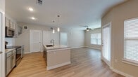 This well-appointed single-floor residence offers a thoughtfully designed open-concept layout that seamlessly connects the kitchen, dining, and living areas. The kitchen serves as the centerpiece of the main living space, showcasing a large granite-topped island with an undermount sink, pendant lighting, gray shaker-style cabinetry, a subway tile backsplash, and stainless steel appliances including a range and over-the-range microwave. Light wood-style plank flooring extends throughout the main living areas, complementing the neutral warm-beige wall tones and white trim throughout.

The open living area benefits from abundant natural light through multiple windows fitted with blinds, and is equipped with a ceiling fan. A full-size closet with louvered doors provides convenient storage near the main entry. The bedroom is carpeted for comfort and features a ceiling fan, a window for natural light, and direct access to a well-sized walk-in closet with built-in shelving and hanging rods. The bathroom is finished with granite countertops, gray cabinetry, a single undermount sink, and wood-style flooring that carries the cohesive design language throughout. Clean lines, consistent finishes, and a bright, neutral palette give the entire space a modern and move-in-ready feel.