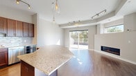 Located in Rochester, MN, this well-appointed residence offers four bedrooms and three bathrooms across a thoughtfully designed single-floor layout. The open-concept kitchen and dining area serves as the heart of the home, showcasing rich dark wood cabinetry, a granite-topped island with pendant lighting, subway tile backsplash, stainless steel appliances including a French door refrigerator and gas range, and track lighting overhead. Warm hardwood floors extend throughout the main living areas, complementing the neutral color palette. The living area features a sleek fireplace and flows naturally toward a wall of sliding glass doors that open to a private balcony, offering scenic tree-lined views and abundant natural light. The generously sized primary bedroom also benefits from direct balcony access through sliding glass doors. Secondary bedrooms feature plush carpeting, clean lines, and ample natural light. Closets are outfitted with custom built-in shelving and drawer systems for optimized storage. Bathrooms are finished with tile flooring and full tub-shower combinations with chrome fixtures. Two hallways connect the spaces efficiently, and the overall ambiance is modern, clean, and move-in ready.