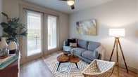 This well-appointed single-floor residence showcases a thoughtfully designed open-concept layout with a cohesive modern aesthetic throughout. The kitchen serves as a central highlight, featuring crisp white shaker cabinetry, granite countertops, a neutral tile backsplash, and a full suite of stainless steel appliances including a refrigerator, electric range with microwave above, and dishwasher. A peninsula island with seating for two is illuminated by pendant lighting, making it ideal for casual dining or entertaining. Light wood-tone luxury vinyl plank flooring runs throughout the main living areas, contributing to a clean, contemporary feel.

The living room is a comfortable, light-filled space with large windows and sliding glass doors that open to a balcony, allowing natural light to fill the room. A ceiling fan adds functional comfort overhead.

The bedroom offers plush carpet flooring, a wide window with outdoor views, and ample space for furnishings. It connects directly to a full bathroom outfitted with white cabinetry, granite countertops, a shower-tub combo with tile surround, and direct access to a generous walk-in closet with built-in shelving and hanging rods. Neutral tones and consistent finishes create a cohesive, move-in-ready environment throughout.