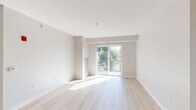 Located at 450 Warrenville Rd in Lisle, IL, this 2-bedroom, 2-bathroom residence offers a clean, modern design across a single floor. The open-concept layout seamlessly connects the kitchen, dining, and living areas, creating a bright and functional living space. The kitchen is a standout feature, outfitted with rich dark wood cabinetry, a herringbone tile backsplash, stainless steel appliances including a refrigerator, range, and built-in microwave, and elegant quartz countertops with an undermount sink. Pendant lighting adds a refined touch overhead. Light hardwood flooring runs throughout the main living areas, while the living room is bathed in natural light from large sliding glass doors that open to a private balcony with outdoor views of surrounding greenery. The two bedrooms feature plush carpeting and generous closet space, including walk-in closets with built-in wire shelving systems. The primary bedroom is spacious and connects to its own bathroom. Both bathrooms are finished with tile flooring, warm wood vanities, and clean white countertops. Additional conveniences include a dedicated laundry room, four closets for ample storage, and a welcoming entrance foyer.