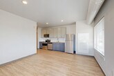 Located at 2065 S Cherokee St in Denver, CO, this single-floor, 2-bedroom, 2-bathroom residence offers a well-designed layout with modern finishes throughout. The open-concept living, dining, and kitchen area forms the heart of the unit, featuring light wood-style luxury vinyl flooring and recessed lighting. The kitchen is outfitted with stainless steel appliances — including a range, microwave, and dishwasher — complemented by two-tone cabinetry with white upper cabinets and gray lower cabinets, a subway tile backsplash, and a undermount sink. A large window in the living area provides natural light and views of the Denver skyline. Both bedrooms are carpeted, each with ceiling fans and ample closet space featuring paneled double doors. The spacious primary bedroom offers a tray ceiling detail and natural light from a window with blinds. Both bathrooms are finished consistently, with white subway tile tub-and-shower surrounds, wood-style flooring, and dark-toned vanities. Additional features include a dedicated laundry area, three closets for generous storage, and an entrance hallway. The unit reflects a clean, contemporary aesthetic with a neutral color palette throughout.