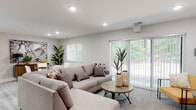This single-floor residence in Wyoming, Michigan, presents a contemporary and well-appointed layout designed for comfortable living. The spacious living area serves as the heart of the home, featuring recessed lighting, light wood-look flooring, and large sliding glass doors framed by vertical blinds that invite abundant natural light and offer views of the surrounding greenery. The open flow between the living space and the adjacent dining and kitchen area creates a cohesive, functional layout.

The kitchen is thoughtfully updated with grey shaker-style cabinetry, marble-look quartz countertops, a classic white subway tile backsplash, and a full suite of stainless steel appliances including a gas range, built-in microwave, refrigerator, and dishwasher. Light wood-look tile flooring ties the space together seamlessly.

The bedrooms are carpeted and well-lit, each featuring windows with outdoor views, warm neutral tones, and ample space. The primary bedroom includes a beam detail and coordinating warm-toned wood furnishings. A secondary bedroom offers a bright, airy aesthetic with natural light.

The bathroom features a granite-top vanity with grey cabinetry, light wood-look flooring, and black hardware accents, maintaining the home's cohesive modern style throughout.