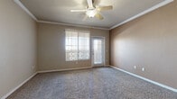 This single-floor residence offers a thoughtfully designed layout with a neutral, warm color palette throughout. The spacious living area is finished with plush carpet, crown molding, and a ceiling fan with light fixture, while large windows with vertical blinds allow generous natural light and outdoor views to fill the room. A dedicated entry point connects seamlessly to the main living space.

The kitchen is well-equipped with rich cherry-toned cabinetry, granite-style countertops, stainless steel appliances including an electric range and over-the-range microwave, and tile flooring. A set of double doors provides additional pantry or storage access, enhancing the kitchen's practicality.

Multiple bedrooms offer comfortable carpeted flooring, ceiling fans, and windows that bring in natural light and views of the surrounding landscape. One bedroom features a built-in shelving unit and walk-in closet area, adding valuable storage.

The bathrooms are finished with warm wood-toned vanities, granite-style countertops, large mirrors, and tile flooring. One bathroom includes a full tub-and-shower combo with sliding glass doors, while the other features a separate water closet layout for added privacy. Overall, the space presents a clean, functional, and comfortable living environment.