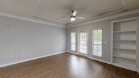 This well-appointed one-bedroom, one-bathroom unit in Lawrenceville, GA offers a thoughtfully designed single-floor layout that maximizes both comfort and functionality. The open-concept living room greets you with warm hardwood-style flooring, crown molding, a ceiling fan, built-in shelving, and large windows with outdoor views that bathe the space in natural light. A paneled accent wall and a private exterior door add character and convenience to the living area. The kitchen is a standout, featuring rich cherry wood cabinetry extending to the ceiling, granite countertops, a glass tile backsplash, a peninsula with an undermount sink, and black appliances including a range, built-in microwave, dishwasher, and refrigerator. Track lighting and crown molding complete the polished look. The spacious bedroom is carpeted for comfort, with a ceiling fan, generous natural light from a large window with outdoor views, and access to a dedicated closet. The bathroom offers a full tub-shower combination with decorative diamond tile accents, a granite-topped vanity, and wood-look flooring. A separate laundry room with full-size washer and dryer hookups adds everyday practicality to this well-rounded home.