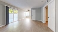 Located in the Beachpointe community of Huntington Beach, CA, this well-appointed one-bedroom, one-bathroom residence offers a thoughtfully designed single-level layout. Light-toned luxury vinyl plank and tile flooring run throughout, complementing soft gray walls and crisp white trim for a clean, modern aesthetic.

The open living and dining area is generously proportioned, bathed in natural light from large sliding glass doors that lead to one of two private patios. A ceiling fan overhead adds comfort, while the patios provide tranquil outdoor space framed by lush mature trees.

The galley-style kitchen is efficiently arranged with white cabinetry, granite countertops, stainless steel appliances including a gas range, microwave, refrigerator, and dishwasher, plus a second patio access door for added ventilation and convenience.

The spacious primary bedroom accommodates a ceiling fan, multiple closets including a walk-in, and an in-unit stacked washer/dryer tucked neatly within the space. The full bathroom features a granite-topped vanity with white cabinetry, a framed mirror, and a shower/tub combination. Three total closets provide ample storage throughout. The layout flows naturally through a central hallway, creating a functional and comfortable living environment.