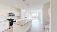 Located at 501 S Capitol Ave in downtown Lansing, Michigan, this contemporary 2-bedroom, 2-bathroom residence offers a thoughtfully designed open-concept layout with modern finishes throughout. The combined kitchen and living area serves as the heart of the home, anchored by a large center island with a quartz-style countertop, undermount sink, and elegant pendant lighting. White shaker cabinetry, a subway tile backsplash, and stainless steel appliances — including a refrigerator with ice maker, range, and over-the-range microwave — complete the chef-friendly kitchen. Light hardwood-style flooring flows through the main living areas, while the living room opens to a private balcony through floor-to-ceiling sliding glass doors, offering sweeping views of the Lansing cityscape and filling the space with abundant natural light. Both bedrooms are carpeted and well-proportioned, with the primary bedroom featuring a generous walk-in closet with wire shelving. The two bathrooms are finished in a clean, modern aesthetic, with the primary bath showcasing a dual-sink vanity with quartz countertops, white cabinetry, and a soaking tub. The second bedroom benefits from a large window with urban views. The overall ambiance is bright, airy, and move-in ready.