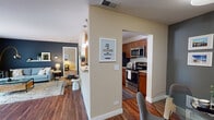 This single-floor residence at 83–85 Sterling Circle in Wheaton, Illinois offers a well-organized open layout that connects the principal living areas in a practical and cohesive flow. Rich hardwood-style flooring extends throughout the main living spaces, anchoring the overall design.

The kitchen is outfitted with warm medium-toned cabinetry, granite countertops, a classic subway tile backsplash, and stainless steel appliances including a range and built-in microwave. A pass-through opening connects the kitchen to the adjacent dining area, which comfortably accommodates a glass-top table and chairs beneath a modern overhead light fixture.

The living room is a standout space, featuring a fireplace flanked by open shelving and a sliding glass door that draws in natural light and provides views of the outdoors. A bold dark accent wall lends visual contrast and a contemporary character to the room.

A hallway leads from the main living area to the bedroom, which features plush carpeting, a generously sized window, and a calm, neutral palette. The full bathroom includes a tub-shower combination with white tile surround, wood-toned vanity cabinetry, and hardwood-style flooring consistent with the rest of the home.