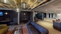Located at 1270 4th Street NE in Washington, DC, this single-floor space blends industrial aesthetics with refined, eclectic design to create a dynamic and versatile environment. The open lounge area serves as the heart of the space, anchored by richly upholstered tufted sofas in deep blue and olive tones, layered over warm hardwood-style flooring and a textured area rug. Dramatic wire-cage pendant chandeliers hang from exposed structural ceilings, casting warm, ambient light throughout and reinforcing the space's industrial character.

Flanking the lounge are glass-paneled private rooms with black steel sliding barn doors, offering intimate meeting or gathering areas adorned with artful wallcoverings and pendant lighting. A bright, windowed alcove provides a quieter retreat, dressed with sheer linen curtains that diffuse natural light and black open shelving for décor and accessories.

The kitchenette area is a design standout, featuring a striking copper fish-scale tile accent wall, dark grey stone countertops, warm wood cabinetry with black hardware, a stainless steel sink with matte black fixtures, and a retro-style black refrigerator. Track lighting completes the functional yet stylish space. Together, these elements create a sophisticated, multi-use venue ideal for gatherings, meetings, or events.