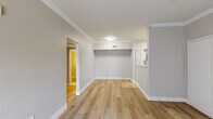 This single-floor space presents a clean, move-in-ready interior with a cohesive neutral color palette and updated finishes throughout. Light-toned hardwood-style flooring runs through the main living areas and bedrooms, lending warmth and continuity to the layout. Crown molding accents the living spaces, adding a polished architectural detail, while generous ceiling height contributes to an open, airy feel.

The main living area is bright and open, with direct access to a sliding glass door dressed with vertical blinds that invite natural light. A ceiling fan overhead provides year-round comfort. Adjacent to the living space, the kitchen is well-appointed with white shaker-style cabinetry, a mosaic tile backsplash, light countertops, a sink with modern fixtures, and stainless steel appliances including a refrigerator and range. Light tile flooring grounds the kitchen and bathroom areas.

The bedrooms are comfortably sized, each featuring light hardwood-style flooring, neutral walls, and windows with horizontal blinds that allow for natural light and privacy. Ceiling fans are present in the bedrooms for added ventilation. The bathroom is functional and clean, featuring a tiled tub-surround with a mosaic accent border, a standard vanity, and tile flooring. Overall, the space offers a well-balanced, practical layout with updated finishes throughout.