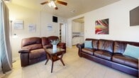 Located at 512 Paulding Ave in Pensacola, Florida, this compact yet efficiently designed one-bedroom, one-bathroom home offers comfortable single-floor living. Light-colored tile flooring runs throughout, creating a cohesive and easy-to-maintain aesthetic across every room. The living room serves as the heart of the home, featuring a ceiling fan with light fixture, a wall-mounted mini-split unit for climate control, and large windows dressed with curtains that invite natural light while maintaining privacy. An open sightline connects the living area to the kitchen, which is outfitted with white cabinetry, a granite-style countertop, a stainless sink, and a white range — offering a clean, functional workspace. The bedroom is a cozy retreat with a ceiling fan, a window overlooking the greenery outside, a built-in closet with hanging rod, and neutral walls that lend a calm atmosphere. The bathroom includes a full tiled tub-shower combination with a classic black-and-white design, complemented by a natural light source from a window. A dedicated laundry room provides added convenience, housing a full-size washer and dryer alongside a window with outdoor views. This home presents a practical and comfortable layout well-suited for Pensacola's coastal lifestyle.