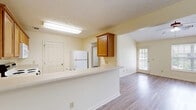 Located at 1801 Century Blvd in Opelika, Alabama, this single-story 2-bedroom, 2-bathroom home offers a functional and comfortable layout across a well-utilized floor plan. The open-concept living and kitchen area forms the heart of the home, where a peninsula breakfast bar connects the kitchen to the living space, creating an easy flow for everyday living. The kitchen is equipped with warm wood-toned cabinetry, a white appliance package including a range, microwave, and refrigerator, and ample counter space with tile flooring. The living area transitions seamlessly to the rest of the home via wood-look plank flooring that extends throughout. Vaulted ceilings in the living and bedroom areas lend an airy, open feel that enhances the sense of space. The spacious primary bedroom features vaulted ceilings, wood-look flooring, and access to a walk-in closet with built-in wire shelving. The second bedroom includes a ceiling fan with light fixture and a natural light-providing window. Both bathrooms are finished with tile flooring, warm wood vanity cabinetry, and full tub-shower combinations. A dedicated laundry room with dryer venting and electrical hookups adds everyday convenience. The home also includes a hallway and additional closet storage throughout.