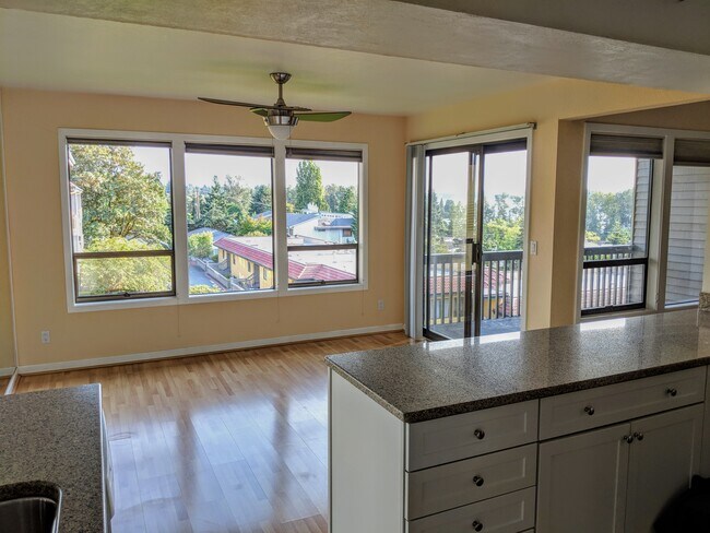 Dining room with view of Lake Washington and downtown Seattle. Also pictured is deck and part of the kitchen. - 11640 100th Ave NE
