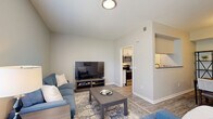 Located at 7987 N Flintlock Rd in Kansas City, MO, this single-floor, 2-bedroom, 2-bathroom residence offers a thoughtfully designed layout that maximizes comfort and functionality. Wood-look flooring flows throughout, complemented by neutral tones and clean lines that give the space a modern, cohesive feel.

The living room is bright and welcoming, with large windows that invite natural light and provide outdoor views. It connects seamlessly to the dining area, which features a dedicated nook framed by open shelving and a pass-through to the kitchen. The kitchen is equipped with stainless steel appliances, including a range and over-the-range microwave, along with white cabinetry and a countertop bar that opens to the dining space.

The generously sized primary bedroom offers a ceiling fan, a window with outdoor views, and direct access to an en-suite bathroom. The primary bath features gray cabinetry, a dual-sink vanity, and leads to a spacious walk-in closet with wire shelving for ample storage. The second bedroom and additional full bathroom provide flexible accommodations for guests or household members. A hallway and dedicated closet round out the practical layout of this well-organized residence.