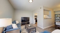 Located at 7987 N Flintlock Rd in Kansas City, MO, this single-floor, 2-bedroom, 2-bathroom residence offers a thoughtfully designed layout that maximizes comfort and functionality. Wood-look flooring flows throughout, complemented by neutral tones and clean lines that give the space a modern, cohesive feel.

The living room is bright and welcoming, with large windows that invite natural light and provide outdoor views. It connects seamlessly to the dining area, which features a dedicated nook framed by open shelving and a pass-through to the kitchen. The kitchen is equipped with stainless steel appliances, including a range and over-the-range microwave, along with white cabinetry and a countertop bar that opens to the dining space.

The generously sized primary bedroom offers a ceiling fan, a window with outdoor views, and direct access to an en-suite bathroom. The primary bath features gray cabinetry, a dual-sink vanity, and leads to a spacious walk-in closet with wire shelving for ample storage. The second bedroom and additional full bathroom provide flexible accommodations for guests or household members. A hallway and dedicated closet round out the practical layout of this well-organized residence.
