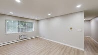 Located at 4117 Gratiot Ave in Fort Gratiot, Michigan, this 2-bedroom, 1-bathroom single-floor unit offers a clean, modern aesthetic with a practical layout. Light hardwood-style flooring runs throughout, complementing the soft neutral gray walls and crisp white trim found across every room.

The open living room is bright and airy, featuring recessed lighting, a wall-mounted HVAC unit, and large windows with blinds that invite natural light. This space flows into the combined dining and kitchen area, which is a clear highlight of the unit. The kitchen is outfitted with white shaker-style cabinetry, rich wood-tone countertops, a herringbone-patterned tile backsplash, a deep stainless steel sink with a matte black faucet, and stainless steel appliances including a gas range, over-the-range microwave, and refrigerator.

Both bedrooms feature the same light flooring and neutral palette, with windows on multiple walls providing excellent natural light and outdoor greenery views. The primary bedroom offers generous proportions, while the second bedroom includes a built-in closet with louvered bifold doors. The unit also features five closets in total, offering ample storage throughout.

The bathroom includes a full tub-shower combination with white square tile surround and a window for natural ventilation. Baseboard heating is present throughout the unit, ensuring consistent warmth.