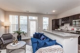 This single-floor residence offers a thoughtfully designed open-concept layout that seamlessly connects the living, dining, and kitchen areas. The living room is bright and welcoming, featuring rich hardwood-style flooring, large windows with horizontal blinds that invite abundant natural light, and a glass-paneled exterior door that enhances the sense of openness. The space accommodates both a relaxed seating arrangement and a dedicated media area, providing functional versatility.

The kitchen is a standout feature, showcasing dark espresso cabinetry with a built-in wine rack, a classic white subway tile backsplash, granite countertops, and stainless steel appliances including a dishwasher, microwave, and range. A peninsula with a white base and granite surface offers additional prep space and serves as a casual dining area. A built-in desk nook adjacent to the kitchen adds a practical workspace.

The bedroom is a serene retreat finished with plush carpet, neutral wall tones, and a ceiling fan with integrated lighting. A spacious closet provides ample storage. The full bathroom features a tiled soaking tub and shower combination enclosed by a sliding glass door, paired with hardwood-style flooring and clean, neutral finishes throughout. Together, these spaces create a cohesive and comfortable living environment.