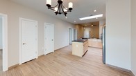 This single-story home offers a thoughtfully designed layout with contemporary finishes throughout. The open-concept kitchen is a standout feature, equipped with light maple cabinetry, dark countertops, a decorative tile backsplash, and a full suite of stainless steel appliances including a gas range, microwave, dishwasher, and French door refrigerator. A central island provides additional prep space and storage. A skylight overhead floods the kitchen with natural light, while recessed lighting ensures consistent illumination. The adjacent dining area is anchored by an elegant chandelier and connects seamlessly to the main living spaces, with large windows drawing in additional daylight.

Wood-look tile flooring flows consistently throughout the home, lending warmth and a cohesive aesthetic. The generously sized primary bedroom features multiple windows, a ceiling fan, and direct access to a well-appointed en-suite bathroom. The en-suite includes a soaking tub with full wood-look tile surround, a built-in niche, a toilet, and a single-sink vanity with a light maple cabinet base and stone-look countertop. A second full bathroom mirrors this design. Additional bedrooms are bright and versatile, each featuring windows that bring in natural light and the same warm wood-look tile flooring, offering comfortable and adaptable living spaces.