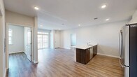 This well-appointed 2-bedroom, 2-bathroom residence at 78 Murray Street offers a thoughtfully designed open-concept layout across a single floor. The combined kitchen and living area serves as the heart of the home, featuring warm wood-look flooring, recessed lighting, and a large sliding glass door that opens to a private balcony, filling the space with natural light. The kitchen is equipped with stainless steel appliances including a gas range, microwave, and French door refrigerator, complemented by dark wood cabinetry, white quartz countertops, a gray subway tile backsplash, and a peninsula with a built-in sink — ideal for both cooking and entertaining. The two bedrooms are generously sized, each with wood-look flooring, neutral tones, and ample closet space among the six closets found throughout the unit. The bathrooms feature stone-look tile flooring, wood-toned vanities with white countertops, and well-lit mirrors. A dedicated laundry room houses a full-size Whirlpool washer and dryer, adding everyday convenience. Clean white walls and consistent finishes throughout create a cohesive, modern aesthetic.