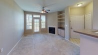 This single-floor residence offers a functional and comfortable layout designed for everyday living. The kitchen is equipped with light wood cabinetry, a full suite of white appliances including a refrigerator and electric range, and a peninsula counter that provides both additional prep space and a natural transition into the dining area. The dining space is accented by an elegant chandelier, creating a warm atmosphere for meals.

The living room is a standout feature of the home, boasting a tile-surround fireplace, built-in shelving and cabinetry, and a ceiling fan. A set of glass-paneled French doors allows ample natural light to pour in and provides direct outdoor access, enhancing the open feel of the space.

The bedrooms are carpeted and offer ceiling fans and windows that bring in natural light. At least one bedroom includes access to a walk-in closet, adding practical storage. Throughout the home, neutral taupe and beige tones create a calm, cohesive aesthetic.

The bathroom features light wood vanity cabinetry with a wide countertop, a large mirror with overhead lighting, and a soaking tub with tiled surround and accessibility grab bars. Tile flooring completes the clean, functional design. Soft carpet runs throughout the main living and sleeping areas, adding warmth and comfort underfoot.