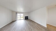 Located at 1555 Sky Valley Dr in Reno, Nevada, this single-floor, 2-bedroom, 2-bathroom home offers a clean, modern aesthetic throughout its well-organized layout. The combined kitchen and living area serves as the heart of the home, where a sleek kitchen impresses with white shaker cabinetry, light quartz countertops, stainless steel appliances—including a range, microwave, and refrigerator—and a deep stainless sink beneath a window that brings in natural light. A peninsula counter provides additional prep space and a natural divider from the living area. The living room features wood-look luxury vinyl flooring, a bold black-framed fireplace, and a sliding glass door that opens to an outdoor view, filling the space with daylight. Both bedrooms are carpeted for comfort and include windows that invite natural light. The primary bedroom offers a generous footprint with closet access. The two bathrooms are finished in a crisp, all-white palette with wood-look tile flooring—one featuring a modern floating vanity with brushed nickel hardware. A connecting hallway ties the layout together efficiently, making this home feel cohesive and functional throughout.