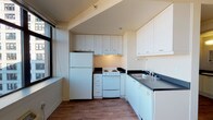 Located at 201 Yesler Way in Seattle's vibrant Pioneer Square district, Unit 1009 is a thoughtfully laid-out single-floor residence that combines functional design with urban convenience. The kitchen is a standout feature, equipped with white cabinetry extending to the ceiling for generous storage, dark countertops, a white electric range, a full-size refrigerator, and a double sink — all complemented by a large window that floods the space with natural light and frames views of the surrounding cityscape. Wood-look flooring runs consistently throughout the unit, lending warmth and visual continuity from room to room. A well-proportioned bedroom includes an open closet with a built-in rod, offering practical storage solutions, and is accented by a wall-mounted sconce. The bathroom features a dark countertop vanity, a toilet, and a towel bar, maintaining the same clean, neutral palette found throughout the unit. A narrow entryway corridor with a wall sconce and electrical panel provides a clear transition into the main living areas. The overall aesthetic is clean and neutral, making the space highly adaptable to a variety of interior styles. Its location in Pioneer Square places residents steps from Seattle's waterfront, dining, transit, and cultural landmarks.