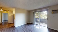 Located at 4295 Clayton Rd in Concord, California, this single-floor unit offers a practical and well-maintained layout with consistent design choices throughout. The living area is a standout feature, characterized by dark wood-style flooring that contrasts cleanly with neutral-toned walls and a textured ceiling. Large sliding glass doors open directly onto a private balcony, framing views of surrounding mature trees and allowing generous natural light to fill the space. A front entryway provides a clear sense of arrival, with the open layout connecting seamlessly to the adjacent kitchen.

The kitchen is efficiently designed in a galley configuration, featuring white shaker-style cabinetry, light quartz countertops, and stainless steel appliances including a range and full-size refrigerator. A window above the counter brings in additional natural light. The bedroom offers a quieter atmosphere with wood-style flooring, neutral walls, and a window overlooking greenery. The bathroom is cleanly finished with white cabinetry, a quartz vanity surface, brushed nickel fixtures, a wide mirror, and a tub-shower combination. Wood-style flooring carries through into the bathroom, contributing to a cohesive aesthetic across the unit.