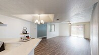 This single-floor residence offers 2 bedrooms and 3 bathrooms within a thoughtfully designed layout. The open-concept living and dining area is anchored by rich wood-look laminate flooring and features dual ceiling fans, a textured ceiling, and a stylish chandelier over the dining space. A pass-through window connects the living area to the kitchen, enhancing the open flow. The kitchen is outfitted with gray shaker-style cabinetry, white quartz countertops, stainless steel appliances including a refrigerator, dishwasher, and range, plus a window above the sink that brings in natural light. Sliding glass doors in the living area open to an outdoor space with views of a community pool and patio. The primary bedroom features plush carpeting, a ceiling fan, a private sliding glass door to an outdoor balcony, and a walk-in closet with distinctive sliding barn doors. The en-suite bathroom includes gray cabinetry, white countertops, and wood-look flooring. A second carpeted bedroom provides a quiet, comfortable retreat. Three bathrooms are distributed throughout, one featuring a clean, all-white walk-in shower. The residence combines functional design with modern finishes throughout.