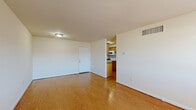 Located at 11054 Warwick Blvd in Newport News, VA, this 2-bedroom, 1-bathroom single-floor home offers a well-organized layout with consistent warm-toned hardwood flooring throughout. The living room greets you at the entry with front-facing windows and a glass-panel door that invite natural light, creating a bright and open atmosphere. The space flows toward a secondary entry door and connects seamlessly to the kitchen. The kitchen features warm wood cabinetry, stone-patterned countertops, and white appliances including a range, microwave, and refrigerator, all arranged in an efficient galley-style layout. Both bedrooms are well-proportioned with natural light provided by windows fitted with blinds. The primary bedroom is generously sized and includes a large closet with folding panel doors, offering ample storage. The second bedroom is a comfortable, light-filled space suitable for various uses. The full bathroom is clean and straightforward, featuring a white tub-shower combination, toilet, and hardwood flooring. Clean white walls and consistent trim work throughout give the home a cohesive, move-in-ready feel. The practical floor plan makes efficient use of every room in this Newport News residence.