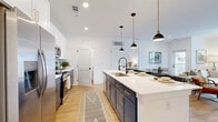Located at 22258 E Quincy Ave in Aurora, CO, this well-appointed 2-bedroom, 2-bathroom single-floor home offers a thoughtfully designed open-concept layout. Light-toned hardwood flooring flows throughout, complementing the bright white walls and creating a cohesive, modern aesthetic. The kitchen is a standout feature, showcasing striking navy lower cabinetry with gold hardware, crisp white upper cabinets, a chevron tile backsplash, and stainless steel appliances. A large central island with a white quartz countertop and an industrial-style pendant lighting trio serves as both a prep space and casual dining area. The adjacent living room is filled with natural light through oversized windows and features a ceiling fan, offering a comfortable and airy atmosphere with balcony access. The primary bedroom provides a serene retreat with natural light and direct access to a beautifully finished en-suite bathroom, which features a double-sink navy vanity with a backlit mirror and a glass-enclosed shower. The second bedroom is equally well-lit and comfortable. A second full bathroom includes a soaking tub with large-format tile surround. Additional spaces include a pantry, laundry room, utility room, and multiple closets for ample storage.
