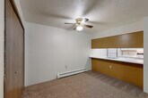 Located at 1082 E Chicago Blvd in Tecumseh, Michigan, this two-bedroom, one-bathroom residence offers a practical and comfortable single-floor layout. The open living area is carpeted and features a ceiling fan with light, baseboard heating, and a sliding glass door that leads to a private balcony with pleasant outdoor views of surrounding greenery. A wall-mounted air conditioning unit provides additional climate control in the living space.

The kitchen is defined by a distinctive pass-through design with a wrap-around white countertop and warm wood-toned cabinetry above and below, creating a functional connection between the kitchen and the adjacent dining area. The kitchen is equipped with a refrigerator and electric range.

The primary bedroom is generously sized and includes a ceiling fan, carpeted flooring, and two sliding wood-paneled closet doors, providing ample storage. The second bedroom also features a ceiling fan and access to a dedicated closet. Throughout the unit, four closets offer considerable storage capacity. The bathroom includes a full tub-shower combination with a clean white surround and tile flooring.

A hallway connects the main living areas to the bedrooms, maintaining a logical and efficient flow throughout the home. Textured ceilings and warm wood-tone trim details are consistent throughout the space.