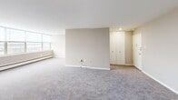 Located at 660 Boas St in Harrisburg, Pennsylvania, this two-bedroom, one-bathroom residence offers a well-organized single-floor layout with a neutral color palette throughout. The open living area is carpeted in a soft gray tone and features large windows that flood the space with natural light while offering expansive views of the Harrisburg cityscape — a standout feature of the unit.

The kitchen is thoughtfully designed with white cabinetry extending to the ceiling for generous storage, marble-patterned countertops, a gas range, built-in microwave, dishwasher, and a stainless steel sink. Light wood-style flooring adds a clean, modern contrast to the bright white finishes. A window above the counter brings in additional natural light.

Both bedrooms are carpeted and feature warm taupe walls, white baseboards, and full-panel bi-fold closets with gold hardware. The primary bedroom is generously sized and offers a comfortable retreat. The second bedroom mirrors a similar aesthetic with ample floor space.

The bathroom includes a full tub-shower combination with yellow ceramic tile walls and matching fixtures, a wall-mounted sink, and a mirrored medicine cabinet. Wood-style flooring ties in cohesively with the rest of the home. This residence combines functional design with elevated city views in a central Harrisburg location.