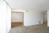 This single-floor unit offers a practical and straightforward layout across several well-defined rooms. The living area is generously sized, finished with neutral-toned wall-to-wall carpeting and a textured ceiling. A large sliding glass door floods the space with natural light and provides access to a private balcony with outdoor views of surrounding greenery.

The kitchen is equipped with rich, dark wood cabinetry both above and below the countertops, complemented by grey laminate counters, a double basin sink, tile backsplash, and white appliances including a dishwasher and electric range. The flooring transitions to light vinyl tile in this area.

The unit includes multiple bedrooms, each carpeted and featuring windows that bring in natural light with views of mature trees. The primary bedroom includes a ceiling fan with light fixture, a closet with bifold doors, and direct access to a bathroom. Additional bedrooms are well-proportioned with ample wall space.

Two bathrooms serve the unit, one featuring a vanity with a yellow-toned countertop, white cabinetry, and a mirrored medicine cabinet, while the other offers a compact layout with tile flooring and a granite-topped vanity.