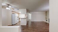 This single-floor, 2-bedroom, 2-bathroom residence in Tucson, Arizona offers a functional and well-organized layout. The open-concept kitchen and living area serves as the heart of the unit. The kitchen is equipped with white appliances including a refrigerator and range, light wood cabinetry, gray laminate countertops, and a peninsula with a sink. A skylight overhead brings natural light into the cooking space, which features wood-style vinyl flooring that extends throughout the main living areas.

The living room is a standout space, highlighted by a tiled fireplace with built-in shelving on one side and a distinctive arched window that allows ample natural light. Sliding glass doors open to an outdoor area, enhancing the connection between interior and exterior. A textured ceiling runs throughout the unit.

Both bedrooms are carpeted and feature neutral walls with windows fitted with vertical blinds. The primary bedroom connects conveniently to one of the two bathrooms, which includes a wide vanity with light wood cabinetry, a large mirror, and wood-style flooring. The second bathroom includes grab bars and hardwood-style flooring. A hallway with a closet connects the main living spaces to the private quarters.