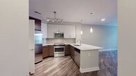 This contemporary one-bedroom apartment offers a harmonious blend of style and functionality within its 690 square feet of living space. The open-concept design creates a seamless flow between the living room and kitchen, optimizing the use of space. The kitchen boasts sleek cabinetry in a two-tone design, with dark lower cabinets and white upper cabinets, complemented by quartz countertops and stainless steel appliances.

The bedroom, measuring 170 square feet, features plush carpeting and ample natural light from large windows. The bathroom is well-appointed with a modern vanity, large mirror, and a bathtub-shower combination. For added convenience, the unit includes an in-unit laundry area with a full-sized washer.

Throughout the apartment, you'll find a cohesive design aesthetic with neutral tones, highlighted by warm wood-look flooring in the main living areas. Ceiling fans in the bedroom and living room provide comfort and air circulation. The balcony offers a private outdoor space, perfect for relaxation or enjoying fresh air.

The property is part of a multi-story residential complex with well-maintained landscaping and communal areas. Its modern architecture, featuring a mix of neutral tones with pops of vibrant color, creates an inviting exterior that complements the interior design of the individual units.