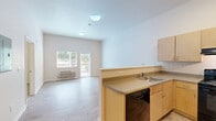 Located at 12201 Washington Center Pkwy in Thornton, Colorado, this single-floor, one-bedroom, one-bathroom residence offers a thoughtfully designed layout that maximizes every square foot of its compact footprint. The open-concept kitchen and living area form the heart of the home, where light wood-look flooring runs throughout, creating a clean and cohesive aesthetic. The kitchen is equipped with light maple cabinetry, ample upper and lower storage, a full suite of black appliances including a range, dishwasher, and refrigerator, and a built-in countertop workspace. A half-wall pass-through connects the kitchen to the living room, which is bright and airy thanks to a large window and a sliding glass door that opens to the outdoors, flooding the space with natural light. The bedroom is a generously sized retreat featuring plush carpeting, a window with outdoor views, and a baseboard heating unit. A well-lit hallway connects the main living spaces to the full bathroom, which features wood-look flooring, a light maple vanity with a sink, a large mirror, lighted vanity fixtures, and an accessible walk-in shower with grab bars and built-in shelving. Additional built-in shelving in the hallway provides convenient storage throughout.