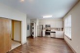 Located at 611 O'Keefe Ave in New Orleans, Louisiana, this well-designed one-bedroom, one-bathroom unit offers a smart and functional layout across a single floor. The open kitchen serves as the heart of the space, outfitted with stainless steel appliances including a refrigerator, range, microwave, and dishwasher, complemented by light wood-toned cabinetry, white countertops, and a subtle tile backsplash. A large window floods the kitchen and dining area with natural light, enhancing the warm hardwood-style flooring that flows throughout the main living areas. A stacked in-unit washer and dryer adds everyday convenience. A hallway connects the main living area to the private bedroom, which features plush carpet, a ceiling fan, and a mirrored sliding closet door offering ample storage. A barn-style wood sliding door adds a distinctive design touch. The bathroom is clean and well-appointed, featuring a full tub and shower combination with classic white subway tile surround and brushed nickel fixtures. Neutral tones throughout create a calm, cohesive ambiance, making this a practical and comfortable space in the heart of New Orleans.