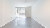 Located at 821 N Fairfax Avenue in the vibrant West Hollywood neighborhood of Los Angeles, this thoughtfully designed one-bedroom, two-bathroom residence offers a clean, modern aesthetic throughout its single-floor layout. The open-concept living and kitchen area is anchored by wide-plank hardwood flooring and floor-to-ceiling glass doors that invite abundant natural light and provide access to a private outdoor space. The kitchen is well-appointed with dark wood cabinetry, frosted glass upper cabinets, stainless steel appliances including a gas range and French door refrigerator, a metallic mosaic tile backsplash, and a sleek white countertop peninsula with pendant lighting overhead — ideal for both cooking and casual dining. The bedroom features plush carpeting, recessed lighting, a sliding glass door to an outdoor area, and a stylish dark-framed glass sliding partition. Two bathrooms serve the unit: one full bath with a tub/shower combo, dark wood vanity, and large-format tile flooring, and a second bath finished in crisp white. Throughout, the space maintains a consistent minimalist palette of white walls and contemporary fixtures, creating a bright and cohesive living environment.