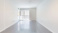 Located at 821 N Fairfax Avenue in the vibrant West Hollywood neighborhood of Los Angeles, this thoughtfully designed one-bedroom, two-bathroom residence offers a clean, modern aesthetic throughout its single-floor layout. The open-concept living and kitchen area is anchored by wide-plank hardwood flooring and floor-to-ceiling glass doors that invite abundant natural light and provide access to a private outdoor space. The kitchen is well-appointed with dark wood cabinetry, frosted glass upper cabinets, stainless steel appliances including a gas range and French door refrigerator, a metallic mosaic tile backsplash, and a sleek white countertop peninsula with pendant lighting overhead — ideal for both cooking and casual dining. The bedroom features plush carpeting, recessed lighting, a sliding glass door to an outdoor area, and a stylish dark-framed glass sliding partition. Two bathrooms serve the unit: one full bath with a tub/shower combo, dark wood vanity, and large-format tile flooring, and a second bath finished in crisp white. Throughout, the space maintains a consistent minimalist palette of white walls and contemporary fixtures, creating a bright and cohesive living environment.