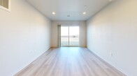 This well-appointed 2-bedroom, 2-bathroom unit at 1600 Indianola Ave offers a thoughtfully designed, single-floor layout with a clean, modern aesthetic throughout. Light wood-tone flooring runs continuously across the space, creating a bright and cohesive feel. The open-concept kitchen and living area serves as the heart of the unit, featuring gray shaker-style cabinetry, light quartz countertops, a double sink, and a full suite of black appliances including a refrigerator, electric range, built-in microwave, and dishwasher. Recessed lighting illuminates the kitchen and living area, which flows naturally toward a sliding glass door opening to a private balcony with outdoor views. The primary bedroom is generously sized and connects to a well-finished en-suite bathroom featuring a wide gray vanity with quartz countertop, a large mirror, and ample storage. The second bathroom includes a white tile walk-in shower with chrome fixtures and wood-look flooring. The second bedroom offers a sliding closet and a window with natural light. A hallway connects the bedrooms and bathrooms with efficient use of space. Throughout, the unit maintains a crisp, neutral palette, making it a versatile and move-in-ready home in Des Moines.