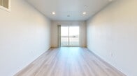 This well-appointed 2-bedroom, 2-bathroom unit at 1600 Indianola Ave offers a thoughtfully designed, single-floor layout with a clean, modern aesthetic throughout. Light wood-tone flooring runs continuously across the space, creating a bright and cohesive feel. The open-concept kitchen and living area serves as the heart of the unit, featuring gray shaker-style cabinetry, light quartz countertops, a double sink, and a full suite of black appliances including a refrigerator, electric range, built-in microwave, and dishwasher. Recessed lighting illuminates the kitchen and living area, which flows naturally toward a sliding glass door opening to a private balcony with outdoor views. The primary bedroom is generously sized and connects to a well-finished en-suite bathroom featuring a wide gray vanity with quartz countertop, a large mirror, and ample storage. The second bathroom includes a white tile walk-in shower with chrome fixtures and wood-look flooring. The second bedroom offers a sliding closet and a window with natural light. A hallway connects the bedrooms and bathrooms with efficient use of space. Throughout, the unit maintains a crisp, neutral palette, making it a versatile and move-in-ready home in Des Moines.