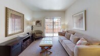 This single-floor residence offers a thoughtfully designed layout that balances comfort and functionality throughout its key living areas. The galley-style kitchen is well-equipped with rich wood cabinetry, granite-style countertops, black appliances including a refrigerator and electric range, a double stainless steel sink, and wood-look flooring that adds warmth underfoot. Adjacent to the kitchen, the dining area features a tray ceiling detail, warm accent walls, and hardwood-style flooring, creating an inviting space for everyday meals. The living room is finished with plush carpet and opens directly to an outdoor patio through a sliding glass door framed by vertical blinds, allowing ample natural light to fill the space. The bedroom is generously sized with soft carpeting, large windows dressed with sheer curtains that invite natural light, and a calm, neutral color palette. The bathroom includes a wood-vanity with granite-style countertop and hardwood-style flooring, with a hallway connecting to a closet and the bedroom beyond. Throughout the residence, neutral tones, consistent finishes, and practical design choices create a cohesive and comfortable living environment.