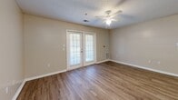Located at 2611 Bemiss Rd in Valdosta, Georgia, this single-floor 2-bedroom, 2-bathroom home offers a practical and well-organized layout throughout. The interior is finished with warm-toned wood-style flooring and neutral beige walls, creating a consistent and cohesive aesthetic across all rooms.

The combined kitchen and living area forms the heart of the home. The kitchen features white cabinetry, a peninsula with countertop overhang, and full appliances including a refrigerator and range. It opens directly to the living room, which is brightened by French doors that provide natural light and outdoor access. A ceiling fan adds comfort to this shared living space.

Both bedrooms are generously proportioned, with the primary bedroom offering notable square footage. Each bedroom includes a sliding double-door closet, a ceiling fan or overhead light fixture, and a window with blinds that allows for natural light and outdoor views. The neutral walls and wood-style flooring continue throughout, giving each room a clean and consistent feel.

The two bathrooms are functionally designed, each featuring a tub-shower combo with grab bars, a toilet, and a single-sink vanity with white cabinetry. Wood-style flooring extends into both bathrooms as well. Additional spaces include a hallway connecting the rooms and a dedicated utility room, rounding out the home's complete and efficient floor plan.