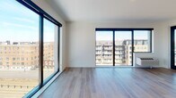 Located at 2264 University Ave W in Saint Paul, MN, this modern single-floor unit showcases a clean, contemporary design throughout. The open living area is a standout feature, bathed in abundant natural light streaming through floor-to-ceiling windows that frame sweeping views of the surrounding cityscape. Light-toned hardwood flooring runs continuously throughout the space, reinforcing a cohesive, airy aesthetic. A glass door provides direct access to a private outdoor balcony, further enhancing the connection to the urban surroundings.

The kitchen is well-appointed with white flat-front cabinetry extending to ceiling height, stainless steel appliances including a French door refrigerator, slide-in range, and built-in microwave, complemented by a tile backsplash and recessed lighting overhead. A peninsula with a white countertop offers additional prep and dining space.

A bright, well-lit hallway connects the living areas to the bedrooms and bathrooms. The bathrooms feature white vanities with undermount sinks, brushed nickel fixtures, large mirrors, and a glass-enclosed shower. Clean white walls throughout maintain a modern, minimalist atmosphere, while recessed lighting ensures consistent illumination across the entire unit.