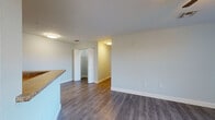 This single-floor unit is designed with a clean, modern aesthetic throughout. The open living area is anchored by wood-style plank flooring in a warm gray tone, complemented by soft neutral wall colors and white baseboards. A ceiling fan with a light fixture provides both comfort and illumination, while vertical blinds on the windows allow natural light to filter in with views of outdoor greenery.

The kitchen features white shaker-style cabinetry, granite-look countertops, and black appliances including a range, refrigerator, and dishwasher. A peninsula with a sink separates the kitchen from the living area, offering a functional and open layout.

The bedrooms are generously sized, each equipped with ceiling fans and windows that invite natural light. Sliding-door closets with built-in wire shelving provide practical storage solutions.

The bathrooms are finished with large-format marble-style ceramic tile flooring and tiled shower surrounds. One bathroom includes accessibility features such as grab bars, indicating thoughtful, inclusive design. Additional storage is accessible via a walk-in closet with wire shelving adjacent to one of the bathrooms.

Overall, the space presents a bright, functional, and cohesive living environment.