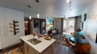 Located at 6811 E Main St in the heart of Scottsdale, Arizona, this single-floor residence offers a thoughtfully designed layout with a distinct mid-century modern flair. The open-concept kitchen is a standout feature, boasting quartz countertops, a large kitchen island with a deep stainless steel sink, stainless steel appliances including a French door refrigerator and gas range, white cabinetry with sleek hardware, a tile backsplash, and pendant lighting overhead. Dark hardwood floors flow seamlessly into the living area, where a vibrant teal sofa, eclectic sunburst wall décor, a ceiling fan, and a sliding glass door leading to a private outdoor balcony create an inviting and lively atmosphere. The balcony overlooks a landscaped outdoor area with palm trees, allowing natural light to fill the room. The bedroom is a serene retreat, featuring plush carpet, sheer draping curtains, a ceiling fan, a statement metallic headboard wall, and ample natural light from large windows. The bathroom is well-appointed with a tub-shower combination, quartz vanity countertop, and tasteful decorative accents. Throughout the space, bold artwork and curated furnishings contribute to a cohesive, vibrant, and welcoming ambiance.