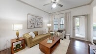 This thoughtfully designed one-bedroom, one-bathroom residence offers a comfortable and functional layout across a single floor. The open-concept living area features wood-style flooring, crown molding, and a ceiling fan, with multiple windows dressed in neutral drapes and blinds that allow generous natural light to fill the space. The kitchen is a standout feature, boasting rich dark-wood cabinetry, granite countertops, black appliances, and a central island with pendant lighting and bar seating — ideal for both cooking and casual dining. The kitchen flows seamlessly into the living area, enhancing the sense of openness.

The bedroom is a well-proportioned retreat with plush carpet, a ceiling fan, and windows that invite natural light. It connects to a spacious walk-in closet equipped with built-in wire shelving and hanging rods, offering substantial storage. The full bathroom features tile flooring, a tub-shower combination with tile surround, a dark-wood vanity with granite countertop, and a large mirror. Throughout the residence, the neutral color palette and consistent finishes create a cohesive, inviting ambiance suited to a variety of personal styles.