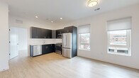 Located on the fourth floor at 22 Schuyler Pl in downtown Morristown, NJ, Unit 403 is a modern 2-bedroom, 3-bathroom residence offering a thoughtfully designed open-concept layout with clean, contemporary finishes throughout. Light wood-look flooring flows seamlessly across the entire unit, creating a bright and cohesive aesthetic.

The open living and dining area connects directly to a well-appointed kitchen featuring dark matte cabinetry with gold hardware, white subway tile backsplash, light countertops, and a full suite of stainless steel appliances including a gas range, built-in microwave, French door refrigerator, and dishwasher. Multiple windows invite natural light and offer views of the surrounding Morristown streetscape.

The spacious primary bedroom includes dual windows with roller shades and a closet. The second bedroom features a built-in shelved closet and its own window with urban views. Both rooms are finished with the same light flooring and crisp white walls.

The three bathrooms offer distinct configurations: one includes a soaking tub with large-format tile surround, while another features a glass-enclosed walk-in shower with hexagonal mosaic floor tile and subway wall tile. The unit's clean, modern design is consistent throughout, making it a polished and functional residence in the heart of Morristown.