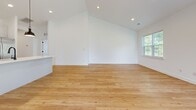 Located at 16384 Granite Way in Milton, Delaware, this well-appointed 3-bedroom, 3-bathroom single-story home offers a clean, modern aesthetic throughout its generously sized floor plan. Light hardwood flooring runs continuously through the main living areas and bedrooms, complementing the crisp white walls and bright, airy atmosphere.

The open-concept kitchen and living room serves as the heart of the home, featuring vaulted ceilings that amplify the sense of space. The kitchen is outfitted with white shaker-style cabinetry accented by matte black hardware, white quartz countertops, a classic subway tile backsplash, stainless steel appliances including a gas range and French door refrigerator, and a center island with pendant lighting.

Each of the three bathrooms is thoughtfully finished with white subway tile, herringbone-patterned tile flooring, white vanities, and sleek matte black fixtures. The spacious primary bedroom offers natural light through large windows with outdoor views.

Additional highlights include dual laundry rooms, five closets providing ample storage, and two entry points for convenience. A covered balcony overlooks a lush green lawn, offering a serene outdoor retreat. The home's modern farmhouse-inspired design and quality finishes make it a standout in the Milton community.